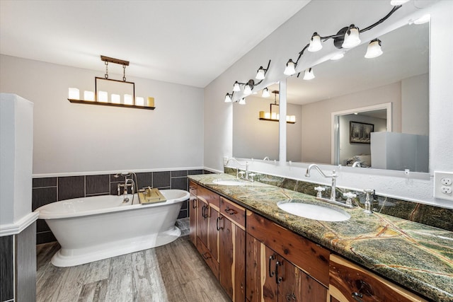 full bathroom with a freestanding tub, wood finished floors, double vanity, and a sink