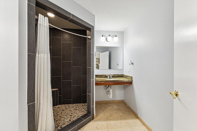 full bathroom with a sink, a shower stall, tile patterned floors, and baseboards