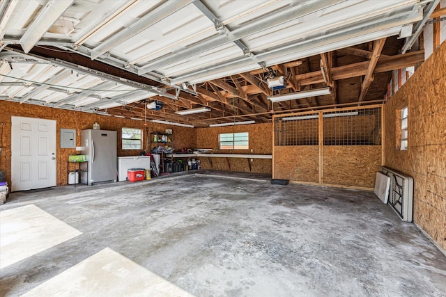 garage featuring a garage door opener, electric panel, and freestanding refrigerator