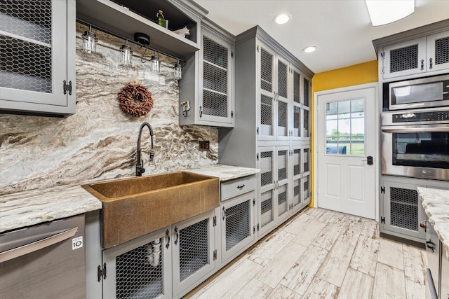 kitchen featuring glass insert cabinets, recessed lighting, a sink, and appliances with stainless steel finishes