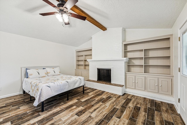 bedroom featuring a brick fireplace, a textured ceiling, vaulted ceiling with beams, and dark wood-type flooring