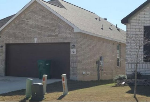 view of side of property with driveway, an attached garage, and brick siding