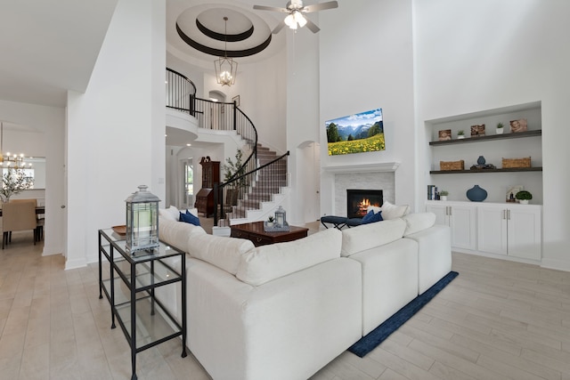 1025 Mission River Dr, Conroe, TX 77304 - living area with stairway, light wood-style floors, a lit fireplace, and a high ceiling