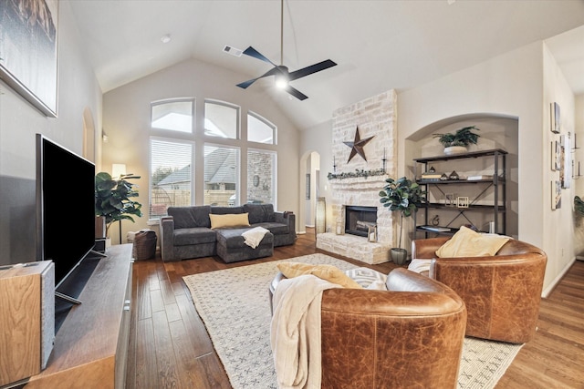 8143 Black Percher St, Conroe, TX 77385 - living room featuring ceiling fan, a stone fireplace, high vaulted ceiling, wood finished floors, and arched walkways
