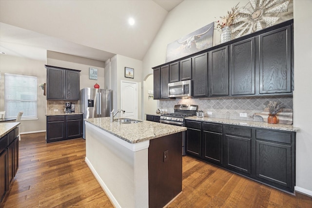 8143 Black Percher St, Conroe, TX 77385 - kitchen featuring appliances with stainless steel finishes, a sink, arched walkways, dark wood finished floors, and backsplash