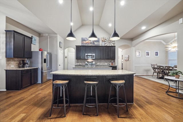 8143 Black Percher St, Conroe, TX 77385 - kitchen with appliances with stainless steel finishes, arched walkways, tasteful backsplash, high vaulted ceiling, and dark wood-style floors