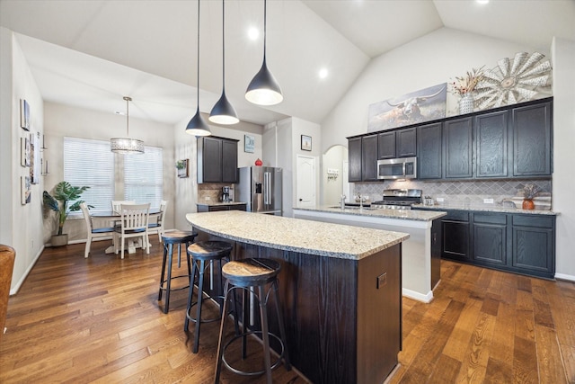 8143 Black Percher St, Conroe, TX 77385 - kitchen featuring stainless steel appliances, a kitchen island with sink, decorative backsplash, dark wood finished floors, and a breakfast bar area