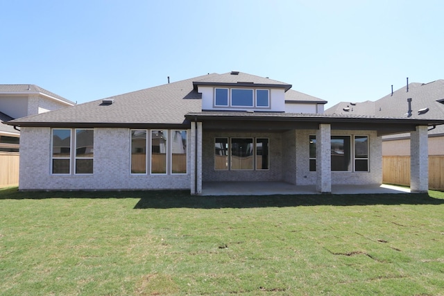 rear view of property featuring a patio, fence, a shingled roof, and a lawn