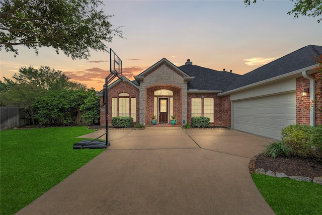view of front of home with brick siding, roof with shingles, a front yard, and concrete driveway