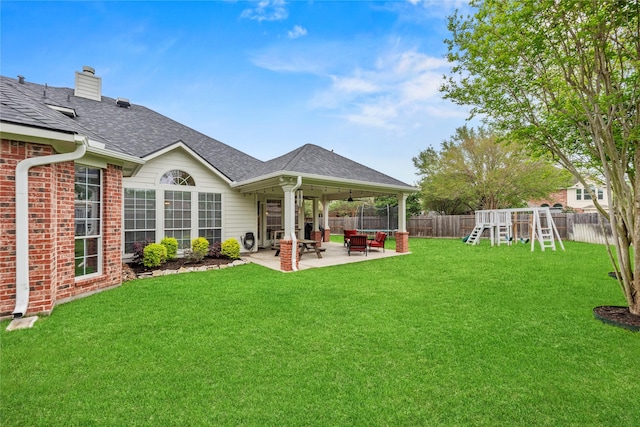 rear view of property with a lawn, a playground, a patio area, and a fenced backyard