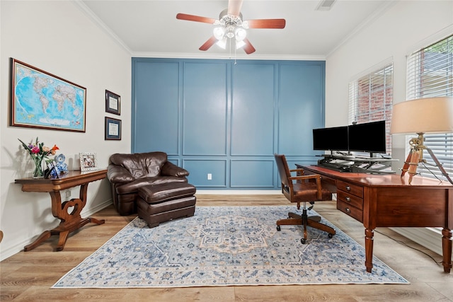 home office with ceiling fan, a decorative wall, light wood-style flooring, visible vents, and ornamental molding