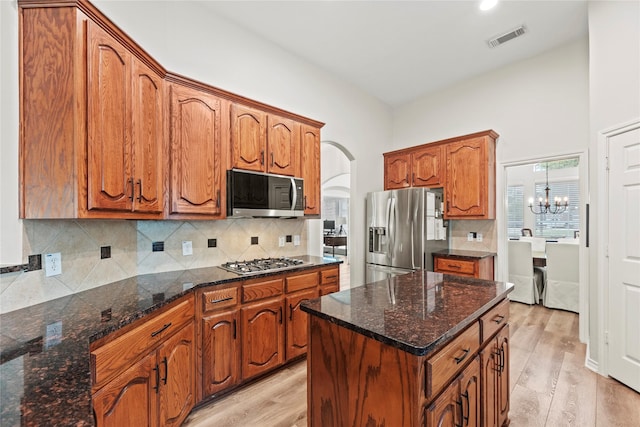 kitchen featuring appliances with stainless steel finishes, brown cabinetry, light wood finished floors, and visible vents
