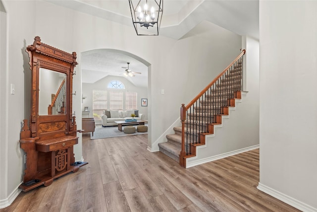 entrance foyer featuring arched walkways, wood finished floors, and stairway
