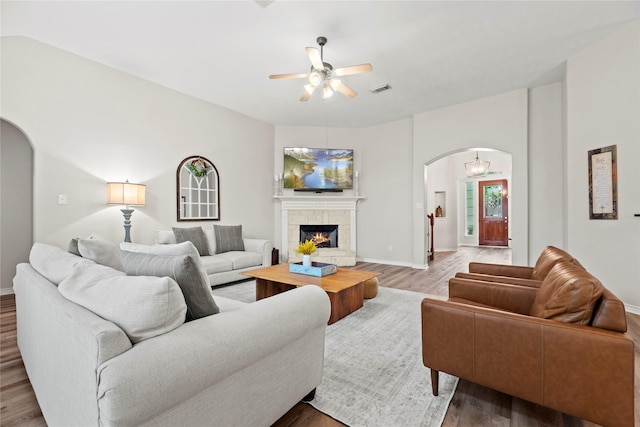 living room featuring arched walkways, ceiling fan, wood finished floors, and visible vents