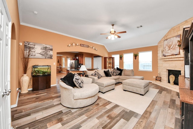 living area with arched walkways, ornamental molding, and light wood-style flooring