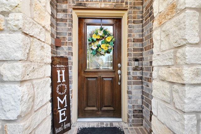 doorway to property featuring brick siding and stone siding