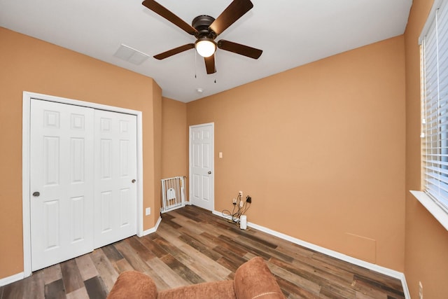 interior space featuring visible vents, a closet, wood finished floors, baseboards, and ceiling fan