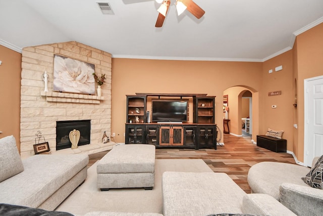 living area with a ceiling fan, visible vents, crown molding, arched walkways, and wood finished floors