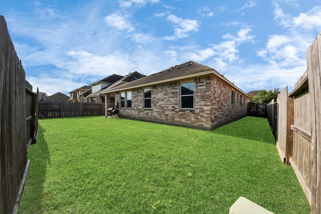 back of house with a lawn, a fenced backyard, and brick siding