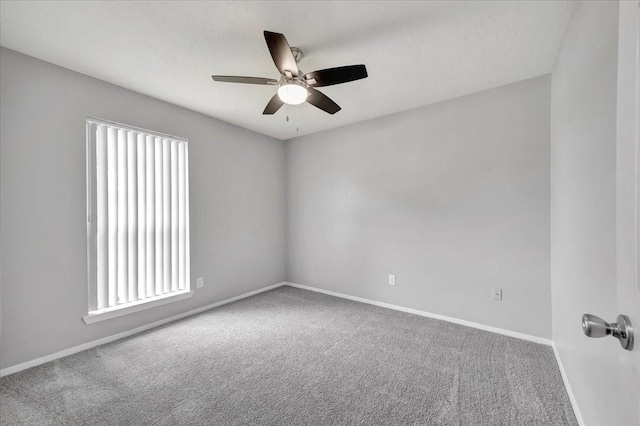 carpeted spare room with baseboards, a ceiling fan, and a wealth of natural light