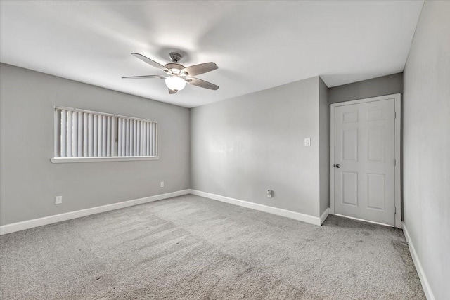 carpeted empty room with baseboards and a ceiling fan