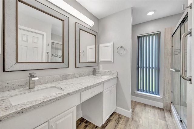 full bath featuring double vanity, wood finished floors, a shower stall, and a sink