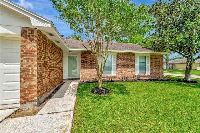 view of front of property with a garage, brick siding, and a front yard