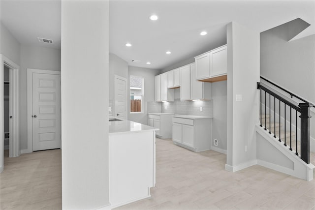 kitchen with tasteful backsplash, recessed lighting, light wood-style floors, white cabinets, and visible vents