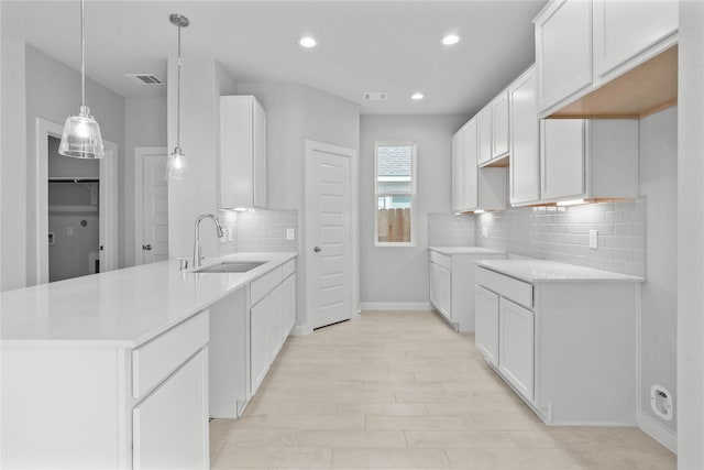 kitchen featuring tasteful backsplash, a sink, baseboards, visible vents, and a peninsula