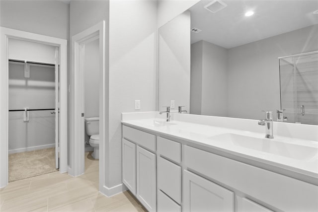bathroom featuring toilet, a sink, a shower stall, and a spacious closet