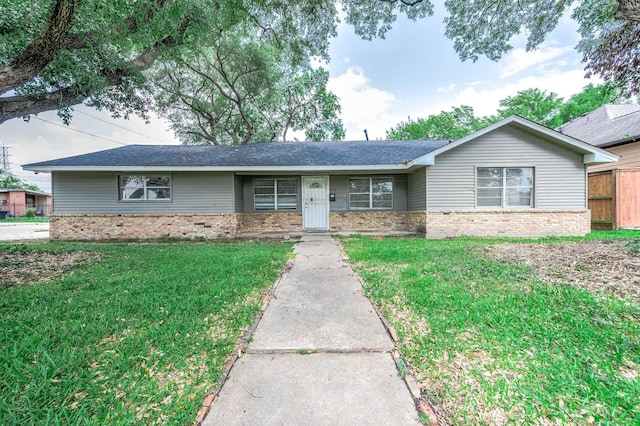 single story home featuring roof with shingles, a front yard, and brick siding