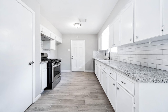 kitchen featuring under cabinet range hood, appliances with stainless steel finishes, white cabinets, backsplash, and visible vents