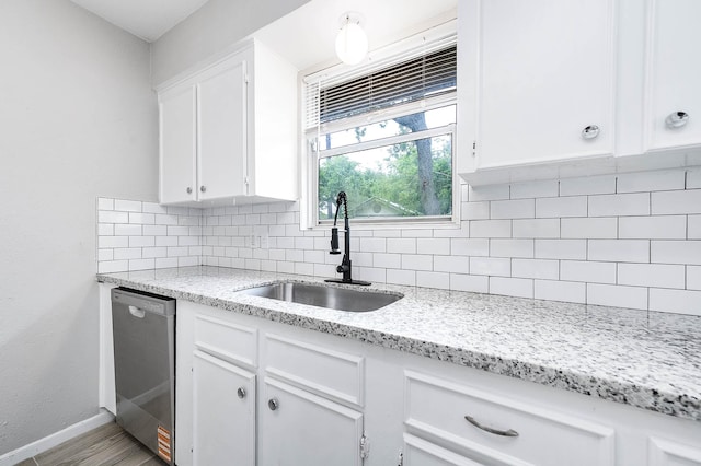 kitchen with white cabinets, a sink, baseboards, dishwasher, and backsplash