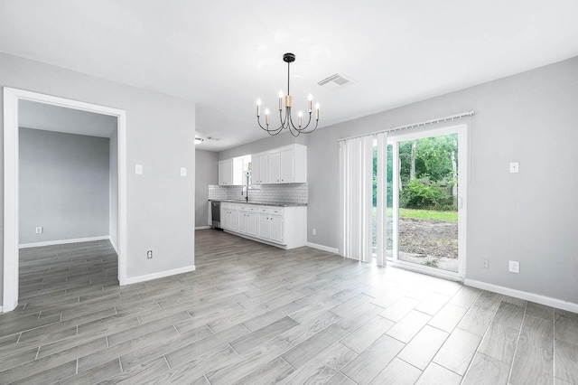 interior space featuring a chandelier, baseboards, white cabinets, and light wood finished floors