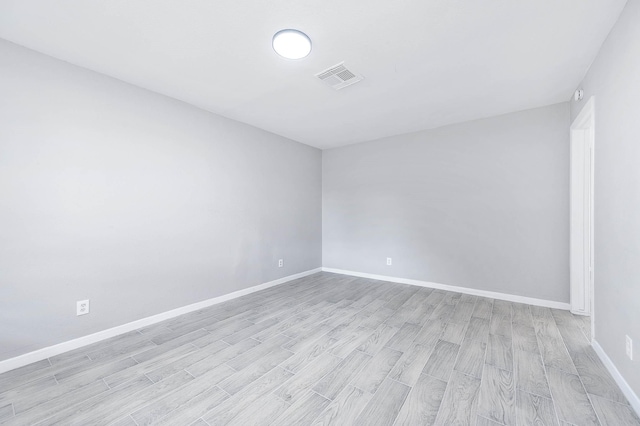 empty room with baseboards, visible vents, and light wood-style floors