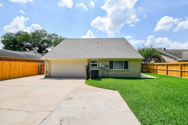 back of house featuring concrete driveway, an attached garage, fence, a yard, and brick siding
