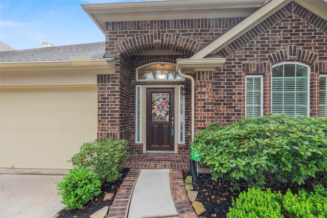 entrance to property with driveway, a garage, and brick siding