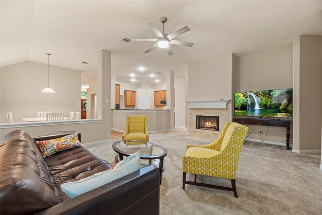 living room featuring lofted ceiling, ceiling fan, a fireplace, and light carpet