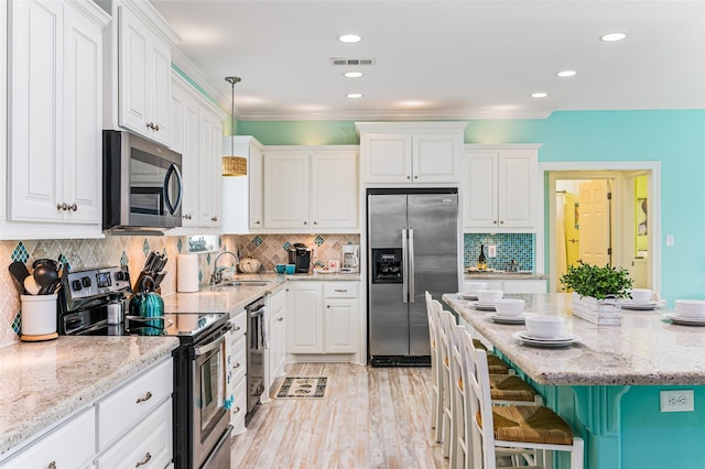 3347 Prides Way, Crystal Beach, TX 77650 - kitchen featuring white cabinetry, a sink, appliances with stainless steel finishes, a breakfast bar, and light stone countertops