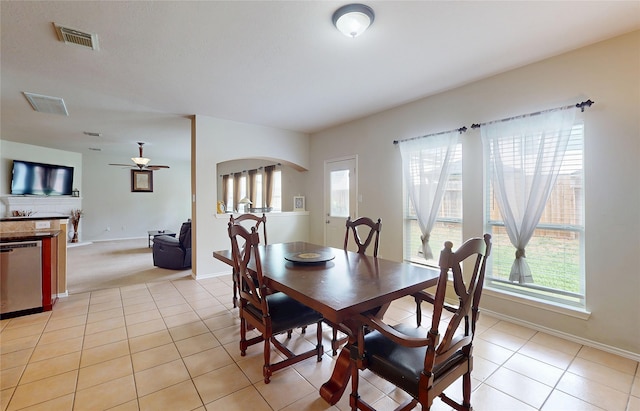 dining area featuring light tile patterned floors, arched walkways, visible vents, and a healthy amount of sunlight