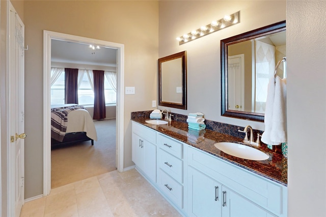 ensuite bathroom with double vanity, ensuite bathroom, baseboards, and a sink