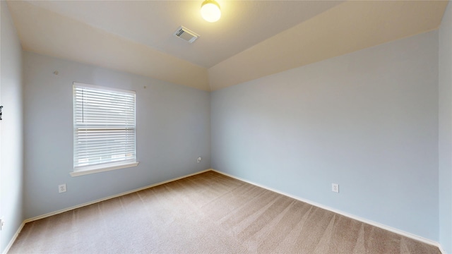 carpeted empty room featuring baseboards, visible vents, and lofted ceiling
