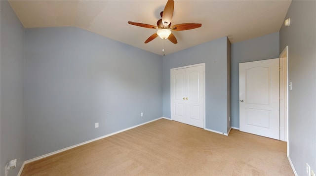 unfurnished bedroom with a closet, carpet, baseboards, a ceiling fan, and lofted ceiling