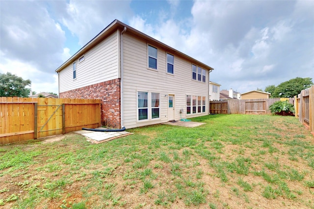 back of property with a gate, a yard, brick siding, and a fenced backyard