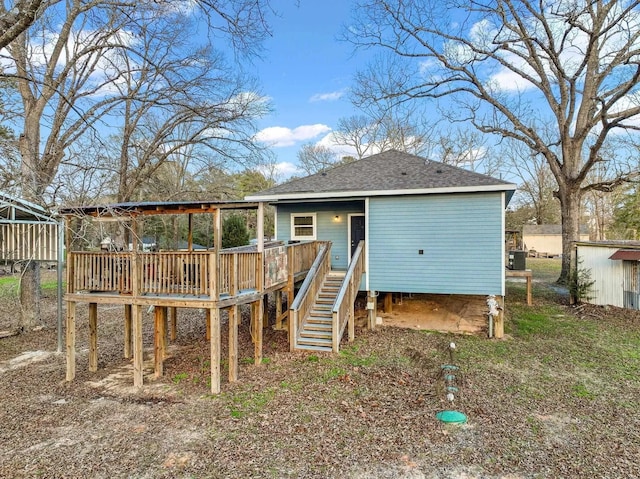back of house with roof with shingles, stairs, and a wooden deck