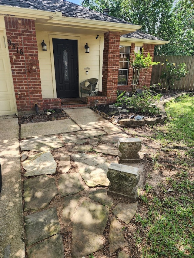 9316 Tejas Ct, La Porte, TX 77571 - doorway to property featuring brick siding, fence, and a shingled roof