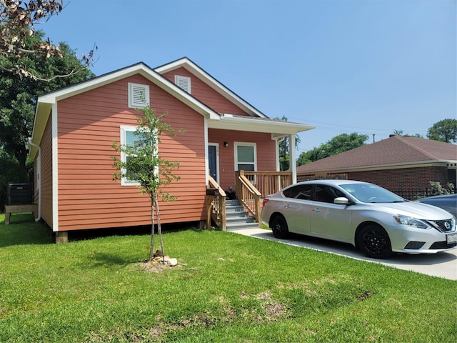 view of front of home featuring a front yard, covered porch, and central AC unit