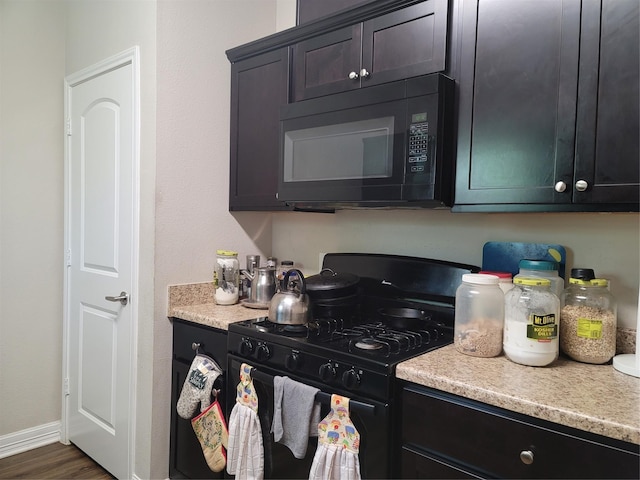 kitchen featuring dark wood-style floors, black appliances, baseboards, and light countertops