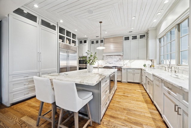 412 Redan St, Houston, TX 77009 - kitchen with built in appliances, custom exhaust hood, a kitchen bar, a kitchen island with sink, and recessed lighting