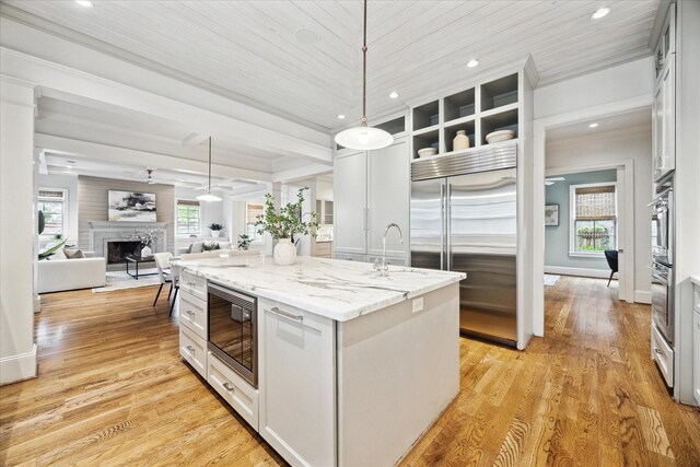 412 Redan St, Houston, TX 77009 - kitchen featuring built in appliances, a center island, a sink, a fireplace, and hanging light fixtures